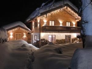 une maison recouverte de neige la nuit avec des lumières dans l'établissement Exklusives Alpenchalet - bis zu 10 Personen, à Bayrischzell