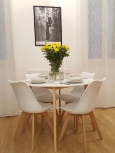 einen weißen Esstisch mit weißen Stühlen und gelben Blumen in der Unterkunft Casa Barzizza in Venedig