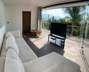 a living room with a white couch and a flat screen tv at Casa de las Aves - Alberca y Jacuzzi climatizados - Espectaculares vistas in Malinalco