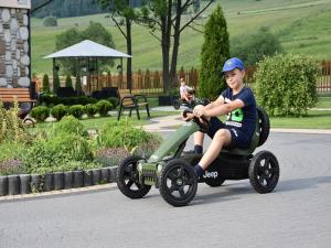 a young boy riding a toy car on a road at Willa Pod Kozińcem in Czarna Góra
