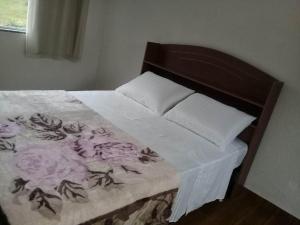 a bed with a white and purple blanket on it at Chalé duplex reformado - Fazenda Cantinho in Teresópolis