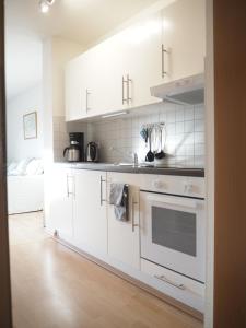 Ferienwohnung preiswert und strandnah في فارنمونده: مطبخ أبيض مع دواليب بيضاء ومغسلة