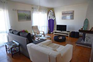 a living room with a couch and a tv at Surf House Peniche in Baleal