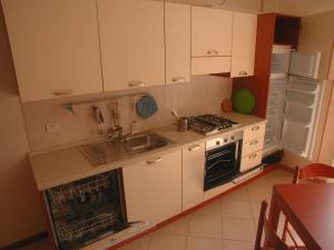 una cucina con armadi bianchi, lavandino e frigorifero di "Il Terrazzo" Apartment a Colico