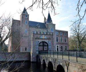 un gran edificio de ladrillo con un puente delante de él en t Laege Uus en Burgh Haamstede