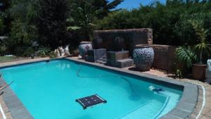 una piscina en un patio con jarrones en la pared en Ville la'Rina, en Ciudad del Cabo