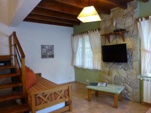 a living room with a tv and a stone wall at Cabañas Tierra Sureña in San Carlos de Bariloche