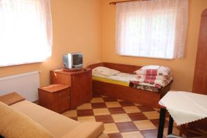 a small room with a bed and a tv in it at Zacisze Konopnickiej in Pobierowo