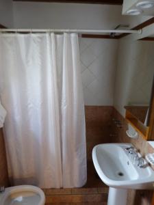 a bathroom with a white shower curtain and a sink at Cabañas Tierra Sureña in San Carlos de Bariloche