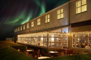 a building with tables and chairs in front of a building with northern lights at Hotel Klaustur in Kirkjubæjarklaustur