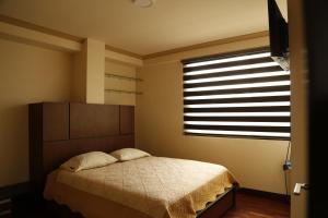 a bedroom with a bed and a large window at San Martin in Cochabamba