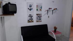 a room with a chair and a tv and posters at Casa de praia em Atalaia in Luis Correia