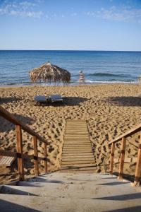 una playa con un paseo marítimo de madera y una sombrilla en The Mini Beach Hotel, en Stalós
