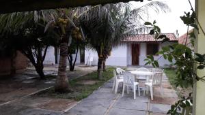 eine Terrasse mit einem Tisch, Stühlen und Palmen in der Unterkunft Casa de praia em Atalaia in Luis Correia