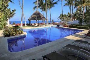 a pool at a resort with palm trees and the ocean at Villa Dorado - Duplex in Sayulita