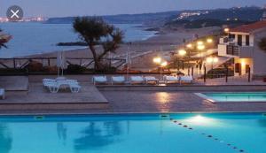 a swimming pool with a view of the beach at night at KAMARINA RESORT in Scoglitti