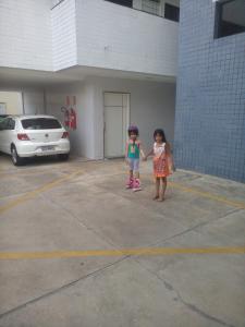 two little girls are shaking hands in a parking lot at Apartamento para temporada in Campina Grande