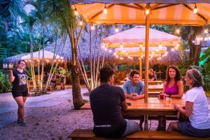 a group of people sitting at a table under an umbrella at The Sunset Shack in Nosara