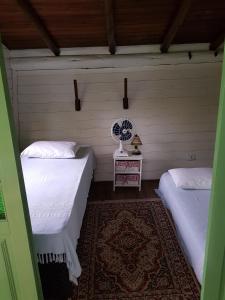 a room with two beds and a table with a fan at Casa do Eduardo in Praia do Rosa