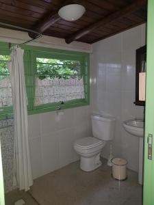 a bathroom with a toilet and a sink and a window at Casa do Eduardo in Praia do Rosa