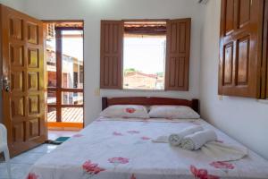 una camera da letto con un letto con due asciugamani e due finestre di Pousada & Kitnet Nascer do Sol a Ilha de Boipeba