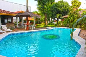 einen Pool mit Sonnenschirm neben einem Haus in der Unterkunft Ross Char Hotel in Asunción