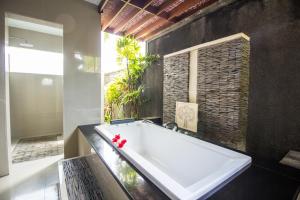 a large white tub in a bathroom with a window at Amore Villas in Canggu