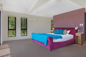 a bedroom with a large bed with a purple headboard at Blu-Sea 365 in Bicheno