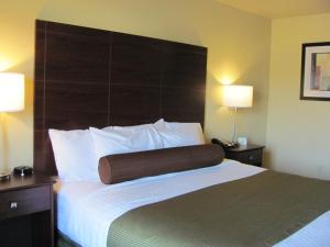 um quarto de hotel com uma cama grande e uma grande cabeceira em Cobblestone Inn & Suites - Ambridge em Ambridge
