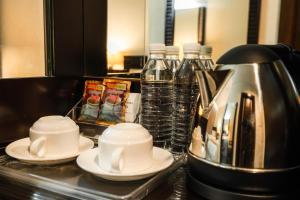 a kitchen counter with plates and a coffee pot and water bottles at Hotel S Damansara in Kuala Lumpur