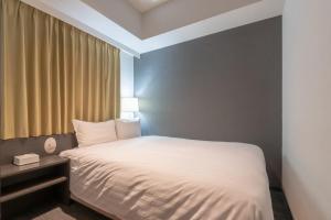 a bedroom with a white bed and a window at E Hotel Higashi Shinjuku in Tokyo