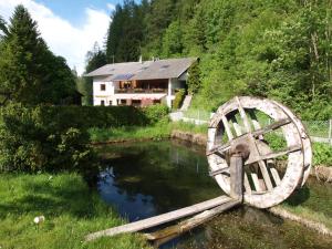 une roue en bois assise dans l'eau devant une maison dans l'établissement Ferienwohnung Kirchbrücke, à Mieders