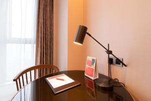 a desk with a lamp and a book on it at Ramada Plaza Wyndham Wenzhou Cangnan in Wenzhou