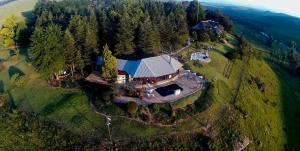 eine Luftansicht eines Hauses auf einem Hügel mit Bäumen in der Unterkunft Amazian Mountain River Lodge in Underberg