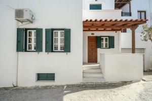 ein weißes Haus mit grünen Rollläden und einer Tür in der Unterkunft NAXOS HOUSE in Naxos Chora