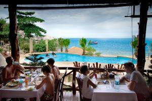 a group of people sitting at a restaurant with a view of the ocean at Montalay Beach Resort - SHA Plus in Ko Tao
