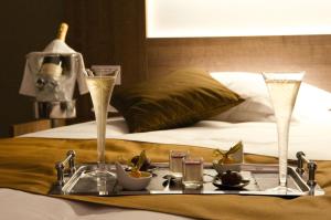 a tray with drinks and food on a bed at The Originals City, Hôtel Les Bastides du Gapeau in Solliès-Toucas