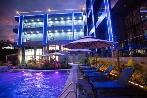 a swimming pool with chairs and umbrellas in front of a building at Vienna Hotel in Coron