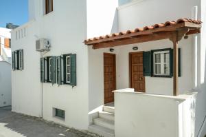 uma casa branca com uma porta de madeira e escadas em NAXOS HOUSE em Naxos Chora