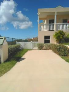 a house with a white fence and a driveway at Beacon Rise Apartment in Basse Terre Town