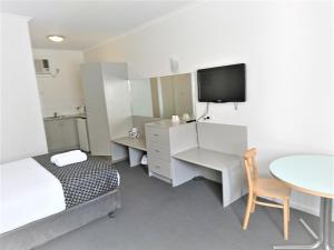 格莱内尔格Glenelg beach gateway Studio Apartment的一间带床、桌子和电视的卧室
