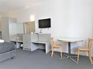 een kamer met een bureau, een tafel en een televisie bij Glenelg beach gateway on Moseley in Glenelg