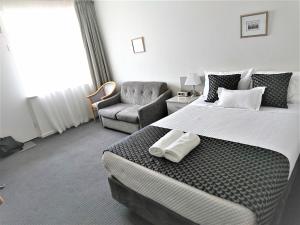 格莱内尔格Glenelg beach gateway Studio Apartment的配有一张大床和一把椅子的酒店房间