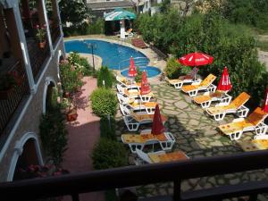 a group of lounge chairs and umbrellas next to a swimming pool at Byala Perla Family Hotel in Byala