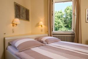 ein Schlafzimmer mit einem Bett mit zwei Kissen und einem Fenster in der Unterkunft Gästehaus Hebinger am Schlosspark in Deidesheim