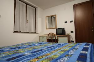 Dormitorio con cama, escritorio y TV en Albergo Ristorante Sciatori, en Pievepelago