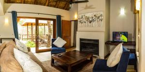 sala de estar con sofá y chimenea en Raptors Lodge, en Hoedspruit