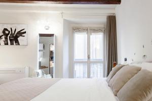 a white bed sitting in a bedroom next to a window at Moscova Luxury B&B in Milan