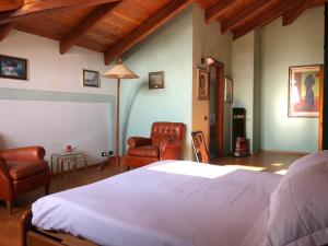 a bedroom with a white bed and two chairs at Villa Bonelli Bed & Fest in Savigliano
