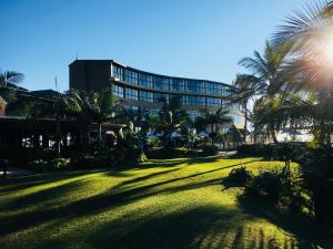 a large lawn with palm trees in front of a building at Salt Rock Hotel and Beach Resort in Ballito